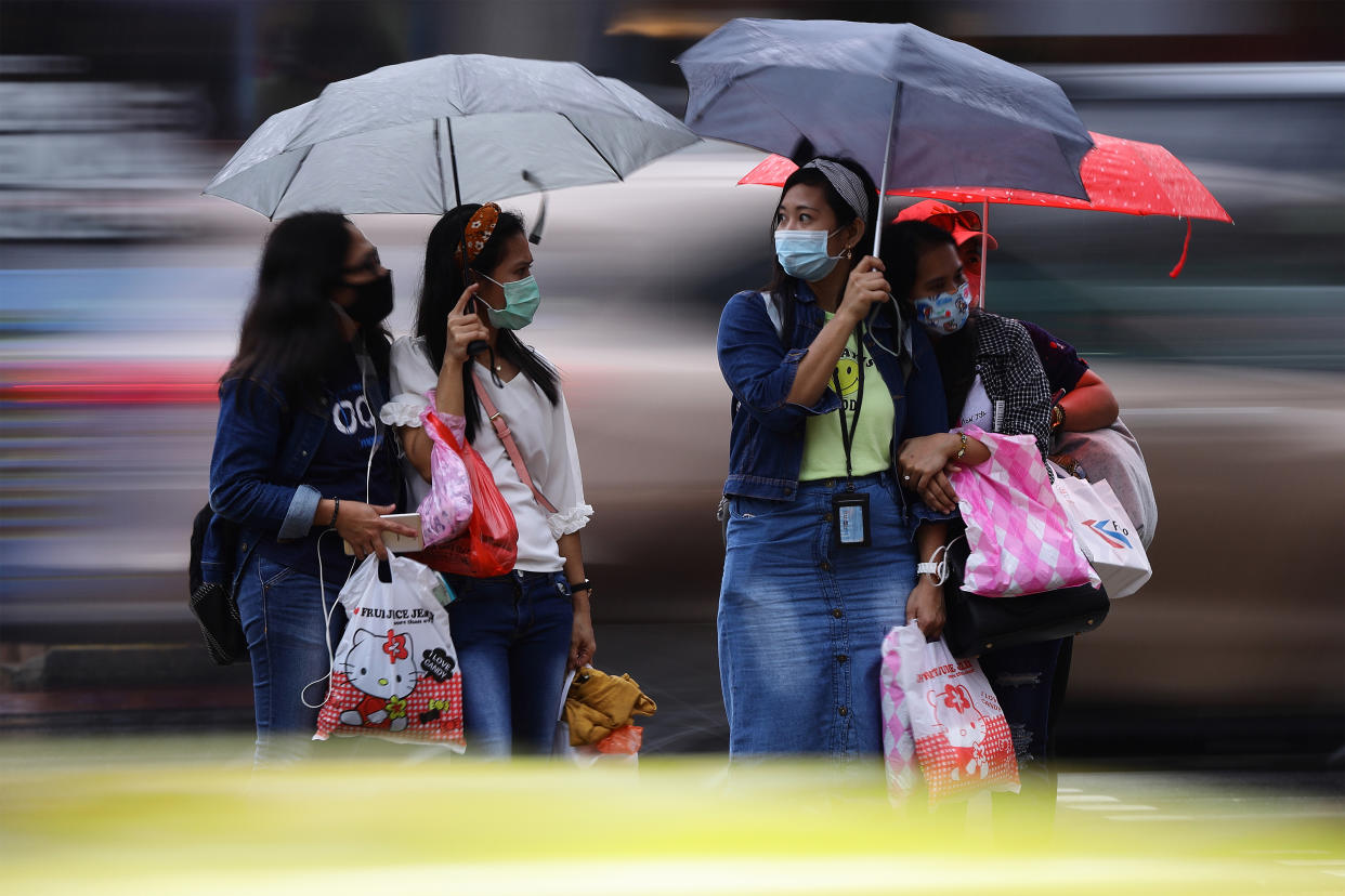 People seen waiting in the rain to cross a street in Singapore on 10 January. (PHOTO: Getty Images)