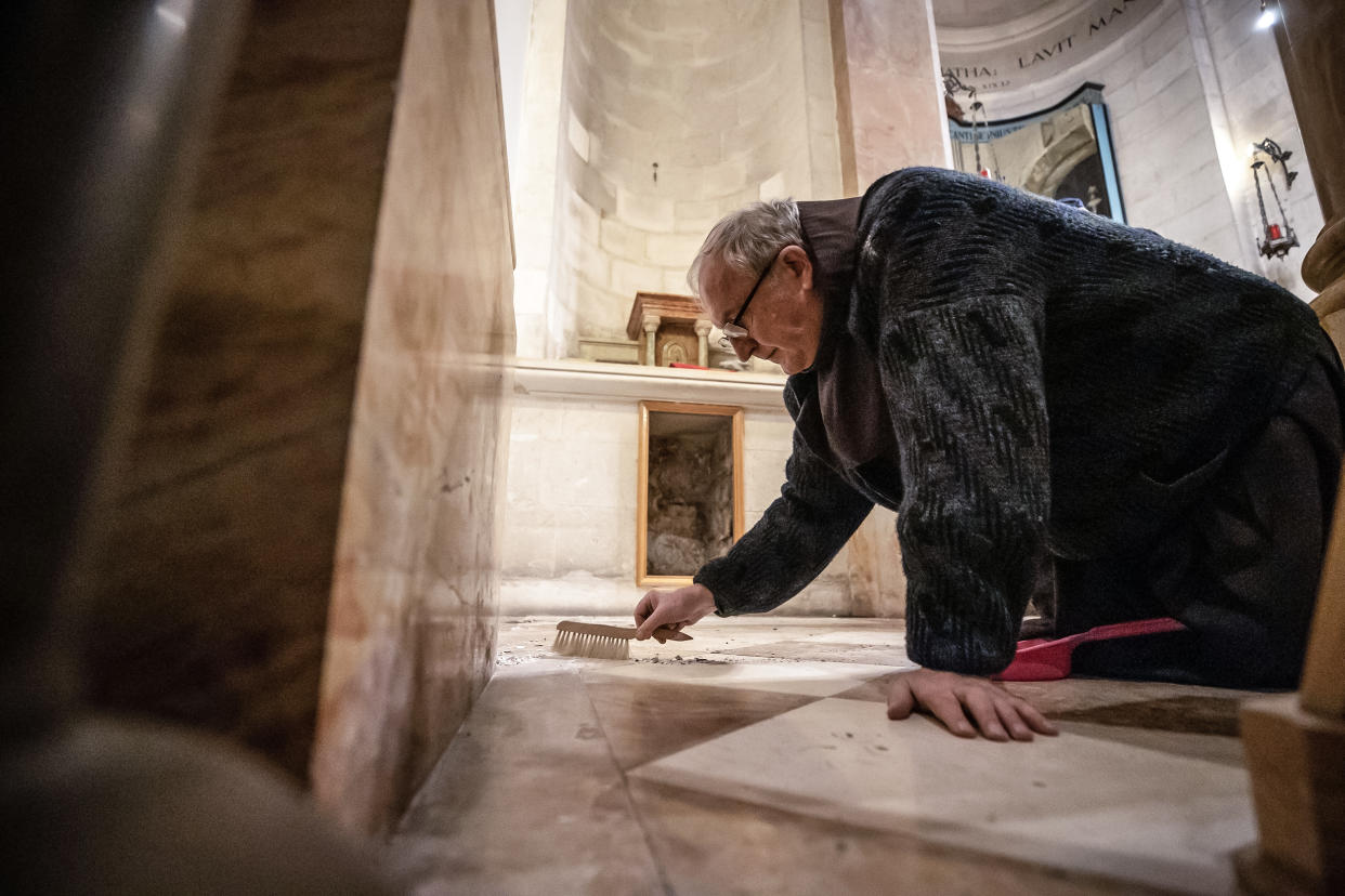 A priest cleans damage after an American tourist attacked and toppled a statue of Jesus in the Church of the Flagellation on the Via Dolorosa in the Old City of Jerusalem on Feb. 2, 2023. (Mostafa Alkharouf / Anadolu Agency via Getty Images file)