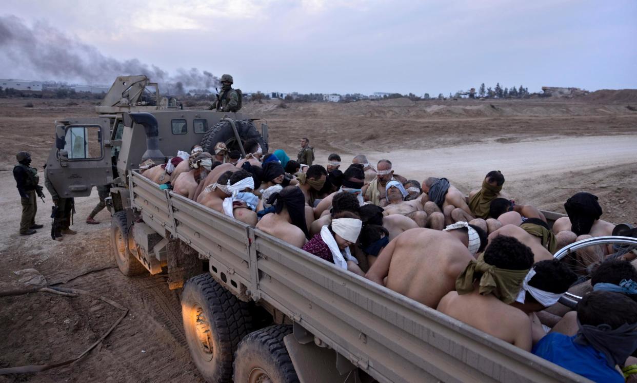 <span>Israeli soldiers guard a vehicle containing bound and blindfolded Palestinian detainees in Gaza.</span><span>Photograph: Moti Milrod/AP</span>