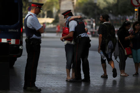 FILE PHOTO: Pilar Revilla, 75, hugs a Catalan Mossos d'Esquadra officer after visiting an impromptu memorial where a van crashed into pedestrians at Las Ramblas in Barcelona, Spain, August 20, 2017. REUTERS/Susana Vera/File Photo