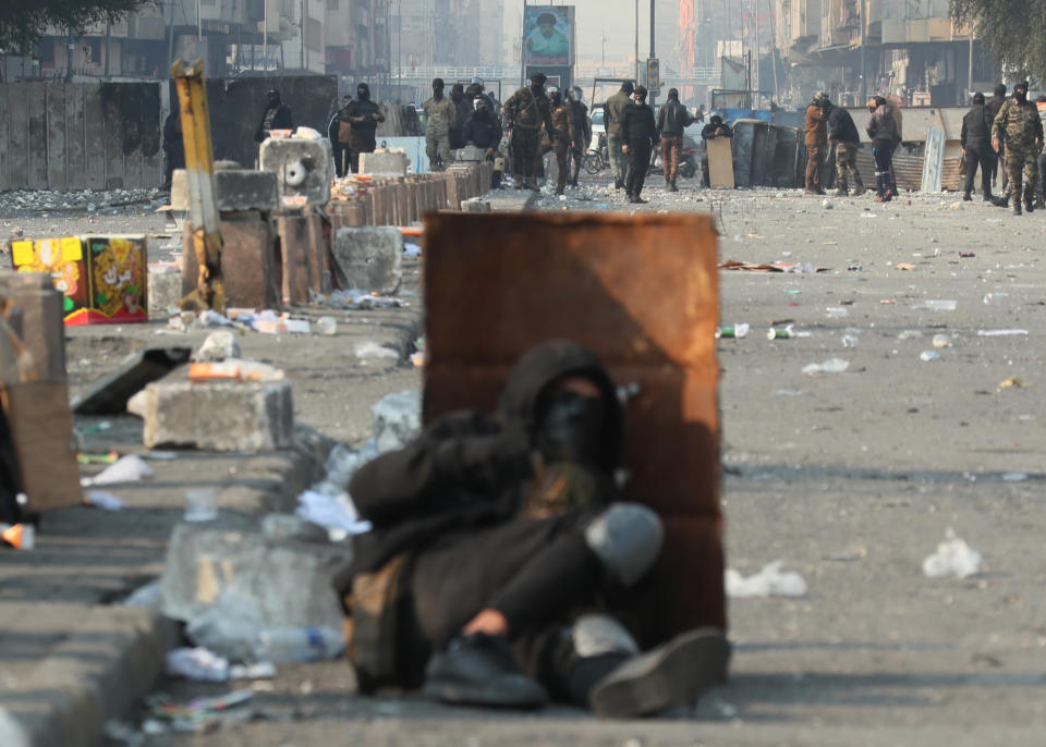 A protester takes cover during clashes with security forces in downtown Baghdad, Iraq, Thursday, Jan. 30, 2020. (AP Photo/Hadi Mizban)