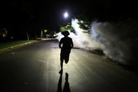 A protester runs away from tear gas in a neighborhood as police disperse the area during a protest after a not guilty verdict in the murder trial of former St. Louis police officer Jason Stockley, charged with the 2011 shooting of Anthony Lamar Smith, who was black, in St. Louis, Missouri, U.S., September 15, 2017. Photo taken September 15, 2017. REUTERS/Lawrence Bryant