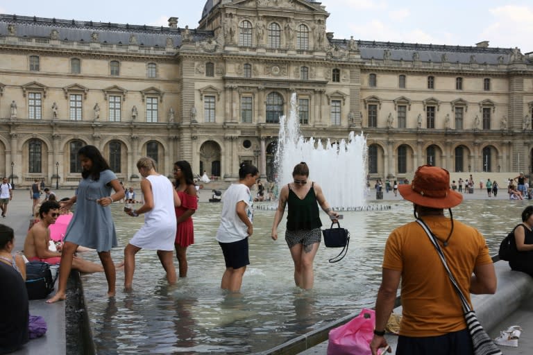 People cool off in a fountain pool near the Louvre Museum as temperatures climb across Europe