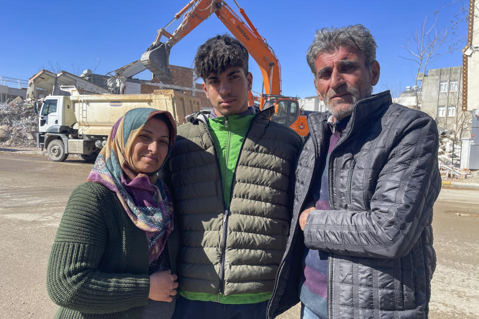 Taha Erdem, 17, center, his mother Zeliha Erdem, left, and father Ali Erdem pose for a photograph next to the destroyed building where Tahan was trapped after the earthquake of Feb. 6, in Adiyaman, Turkey, Friday, Feb. 17, 2023. Taha Erdem, a resident of southeastern Turkey's Adiyaman, is one of the hundreds of survivors pulled out of collapsed buildings after the Feb. 6 powerful quake. Erdem, who is 17, filmed himself on his phone while stuck and sandwiched between concrete in what he thought would be his last words. (AP Photo/Mehmet Mucahit Ceylan)