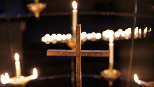 Cruz en el medio de velas prendidas. 