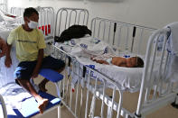 A Yanomami man sits next to a baby, who is receiving medical treatment, at the Santo Antonio Children's Hospital, in Boa Vista, Roraima state, Brazil, Thursday, Jan 26, 2023. Brazil's government declared a public health emergency for the Yanomami people in the Amazon, who are suffering from malnutrition and diseases such as malaria. (AP Photo/Edmar Barros)