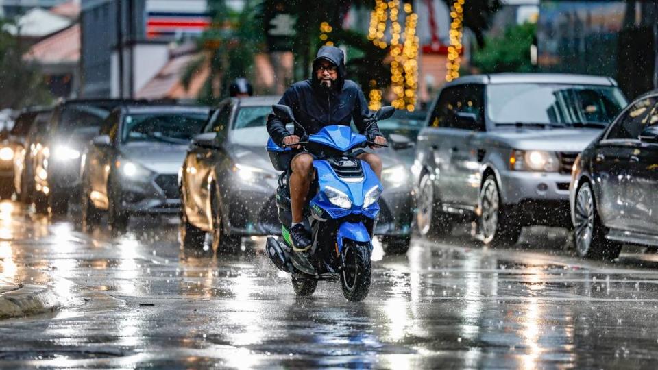 A motorcyclist dodges the rain and motorist while crossing the intersection of South Miami Avenue and 8th Street in Miami on Wednesday, November 15, 2023.