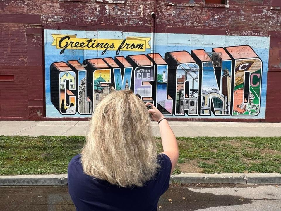 Beatrice Karsenti, of Paris, France, takes a photo of Cleveland mural art during a visit to America earlier this summer.