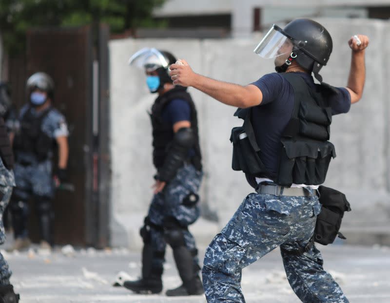 A riot policeman throw a stone at demonstrators during a protest in Beirut