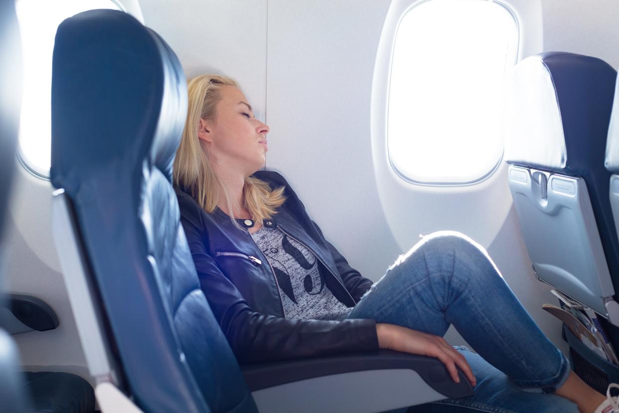 tired woman napping on uncomfortable seat while traveling by airplane