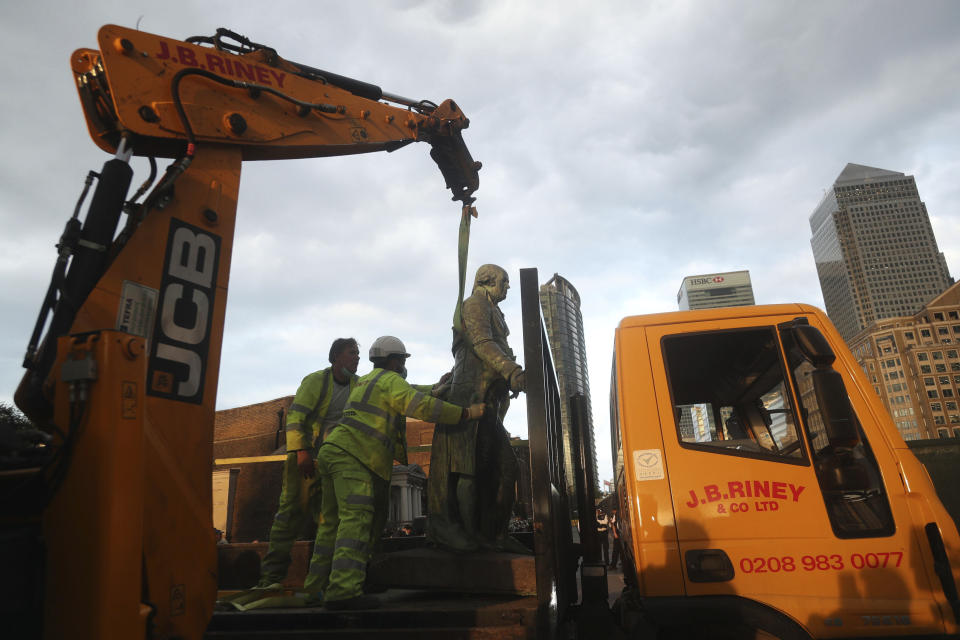 Unos trabajadores sostienen la estatua del propietario de esclavos Robert Milligan, luego de que fue retirada del distrito West India Quay, en el este de Londres, el martes 9 de junio de 2020. (Yui Mok/PA vía AP)