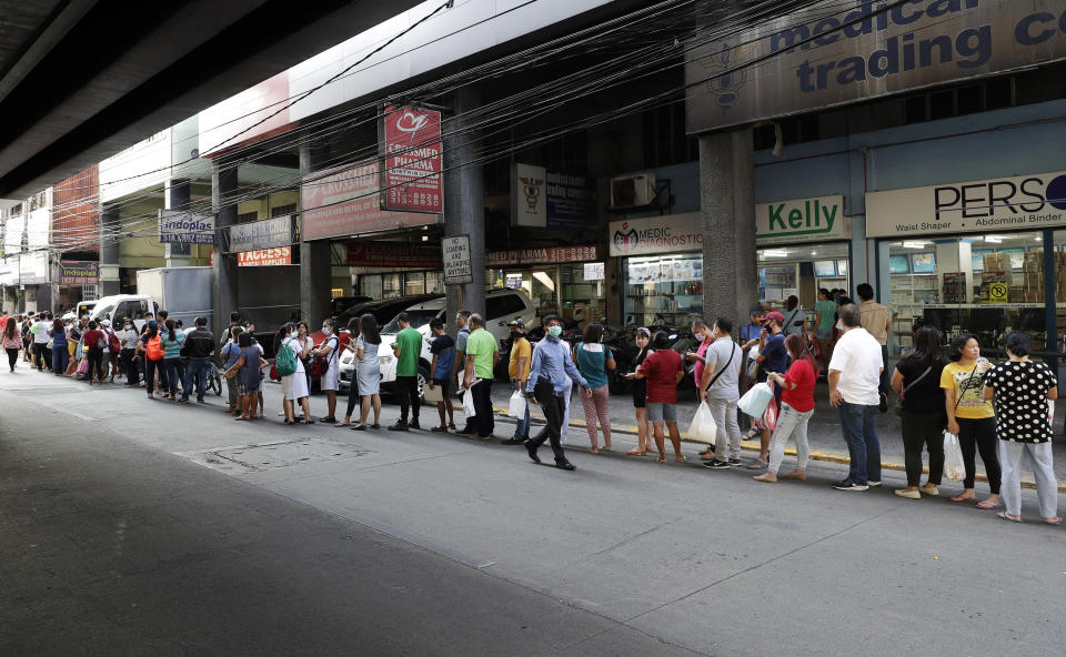 FILE - In this Jan. 30, 2020, file photo, people wait along a road to buy protective face masks at a store in Manila, Philippines. Fear of the spreading coronavirus has led to a global run on sales of face masks despite medical experts' advice that most people who aren't sick don't need to wear them. (AP Photo/Aaron Favila, File)