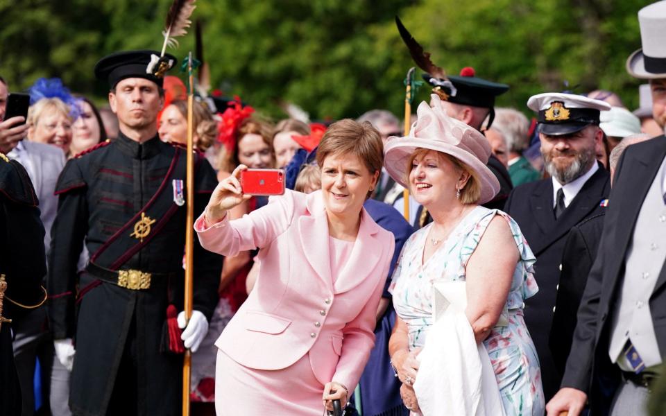 Nicola Sturgeon takes a picture with a guest during a garden party at the Palace of Holyroodhouse in Edinburgh yesterday - Reuters