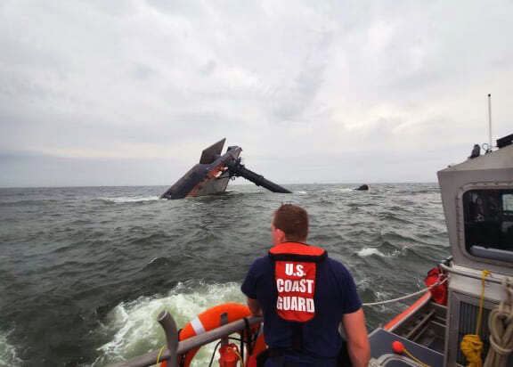 In this photo provided by the U.S. Coast Guard, A Coast Guard Station Grand Isle 45-foot Response Boat-medium boat crew member searches for survivors near the capsized SeaCor Power. The Seacor Power, an oil industry vessel, flipped over Tuesday, April 13, 2021 in a microburst of dangerous wind and high seas. 