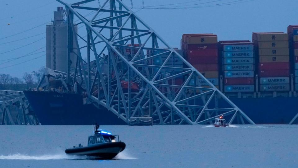 PHOTO: A container ship rests against wreckage of the Francis Scott Key Bridge as night falls on March 26, 2024, as seen from Sparrows Point, Md. (Matt Rourke/AP)