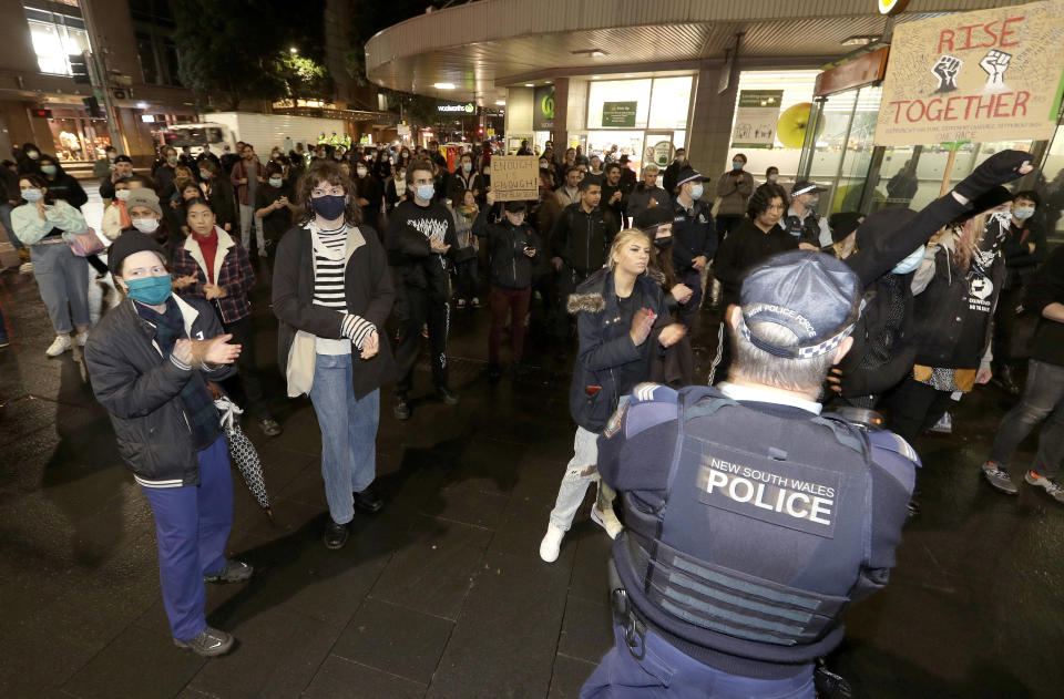 Police watch protesters that gathered in Sydney, Friday, June 12, 2020, to support U.S. protests over the death of George Floyd. Hundreds of police disrupted plans for a Black Lives Matter rally but protest organizers have vowed that other rallies will continue around Australia over the weekend despite warnings of the pandemic risk. (AP Photo/Rick Rycroft)