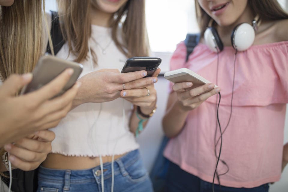 Teenage girls using cell phones in school