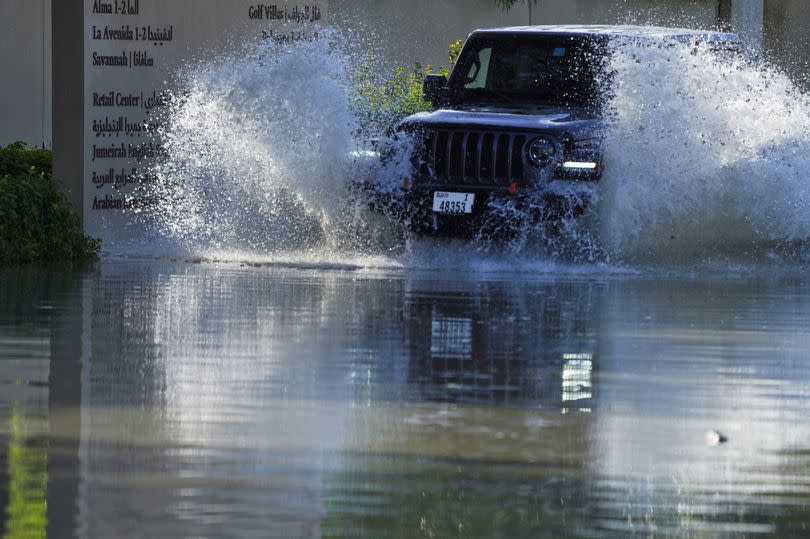 An SUV drives through floodwater covering a road in Dubai -Credit:AP