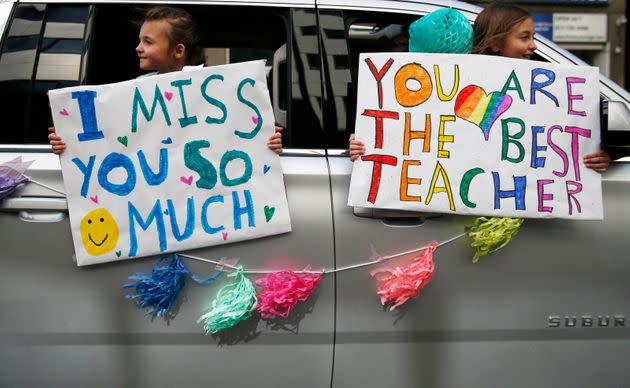 St. John School students hold signs as they drive by their teacher, Megan Congemi, during a surprise parade held in her honor on 