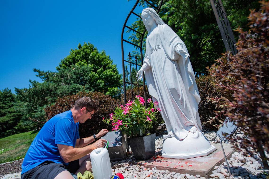 Parishioner Sean Doherty cleans splatters of red paint from a statue of the Virgin Mary on Sunday, July 10, 2022, outside of Ascension Catholic School in Overland Park. The school is adjacent to The Church of the Ascension is at the forefront for Value Them Both campaign, which if passed on Aug. 2, would remove the right to abortion from the Kansas constitution. Caption