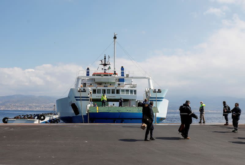 FILE PHOTO: People walk in front of a ferry at the ferry port in the Sicilian city of Messina