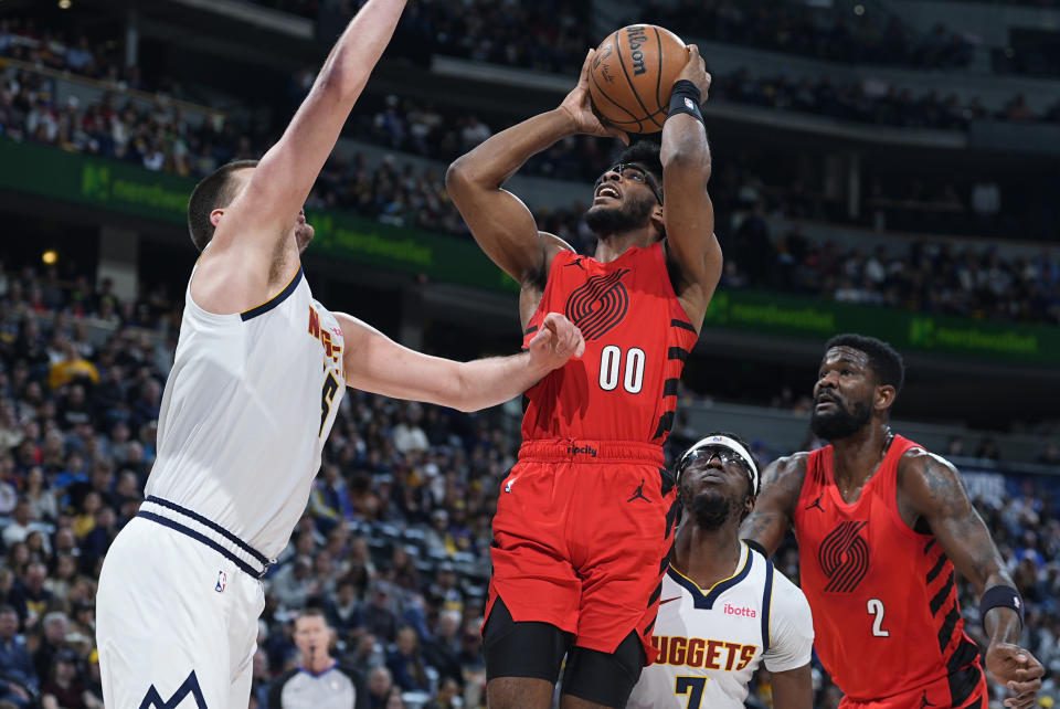 Portland Trail Blazers guard Scoot Henderson, second from left, drives to the basket between Denver Nuggets center Nikola Jokic, left, and guard Reggie Jackson, second from right, as Trail Blazers center Deandre Ayton, right, watches in the first half of an NBA basketball game Sunday, Feb. 4, 2024, in Denver. (AP Photo/David Zalubowski)