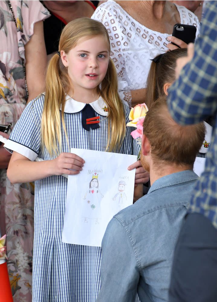 A young fan holds up a picture she drew for Prince Harry and Meghan Markle