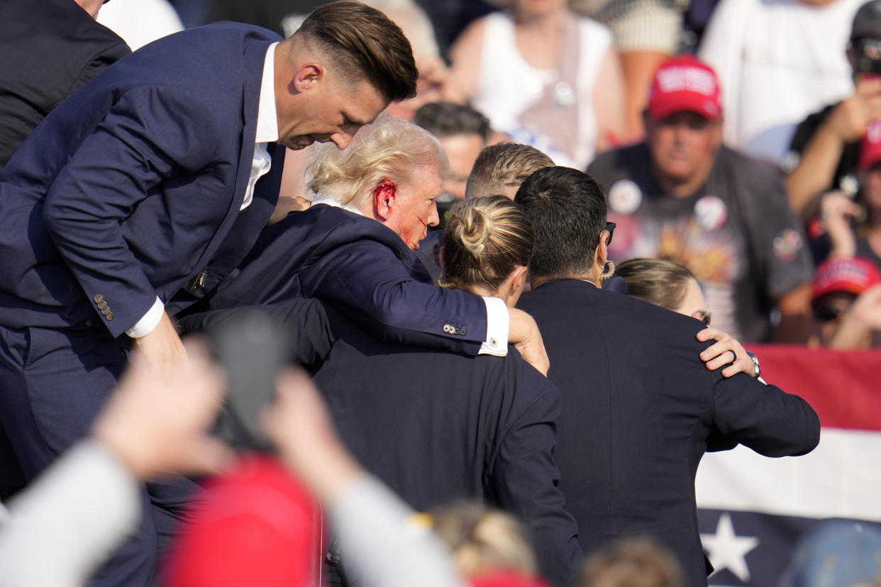 Trump is carried off the stage by Secret Service agents. 