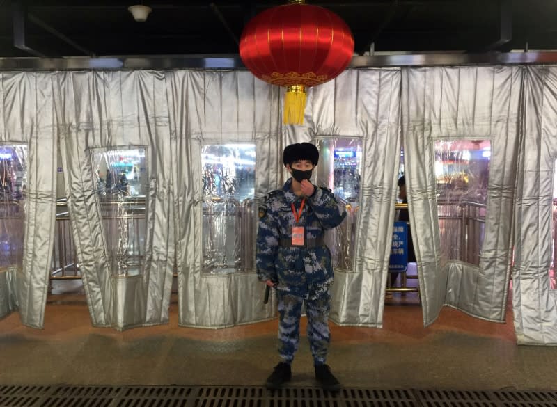 Security personnel wearing a mask stands guard outside the security check at the Beijing West Railway Station, in Beijing