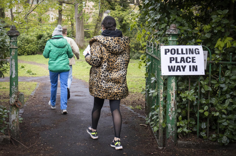 People arrive to vote at a polling station in Glasgow, Scotland, Thursday May 6, 2021. Scots are heading to the polls to elect the next Scottish Government - though the coronavirus pandemic means it could be more than 48 hours before all the results are counted. (Jane Barlow/PA via AP)