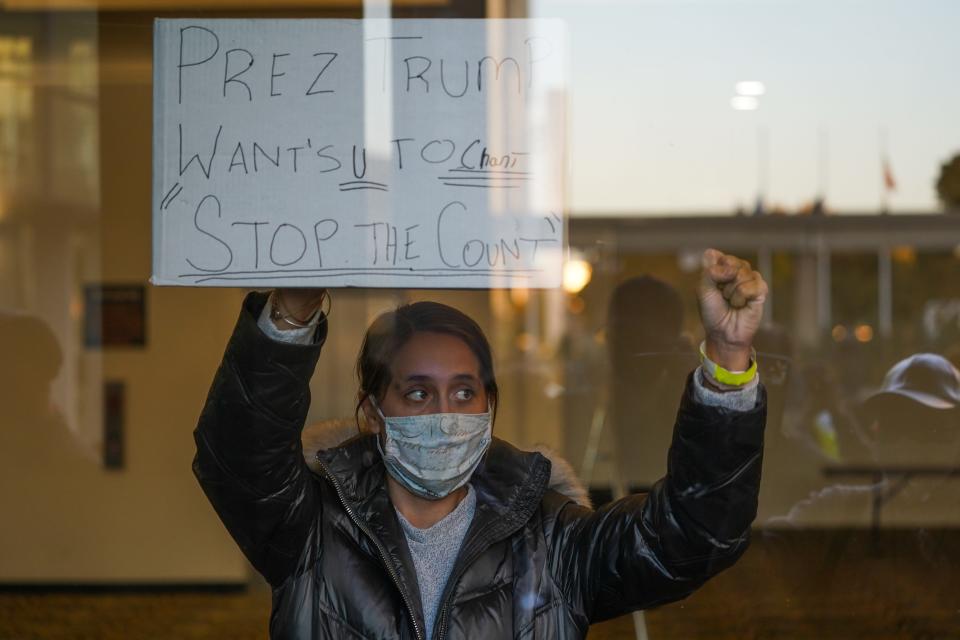 A woman with the Trump campaign holds a sign to get Republican challengers outside the TCF Center to chant, "Stop the count!" as absentee ballots were counted in Detroit on Wednesday, Nov. 4, 2020.