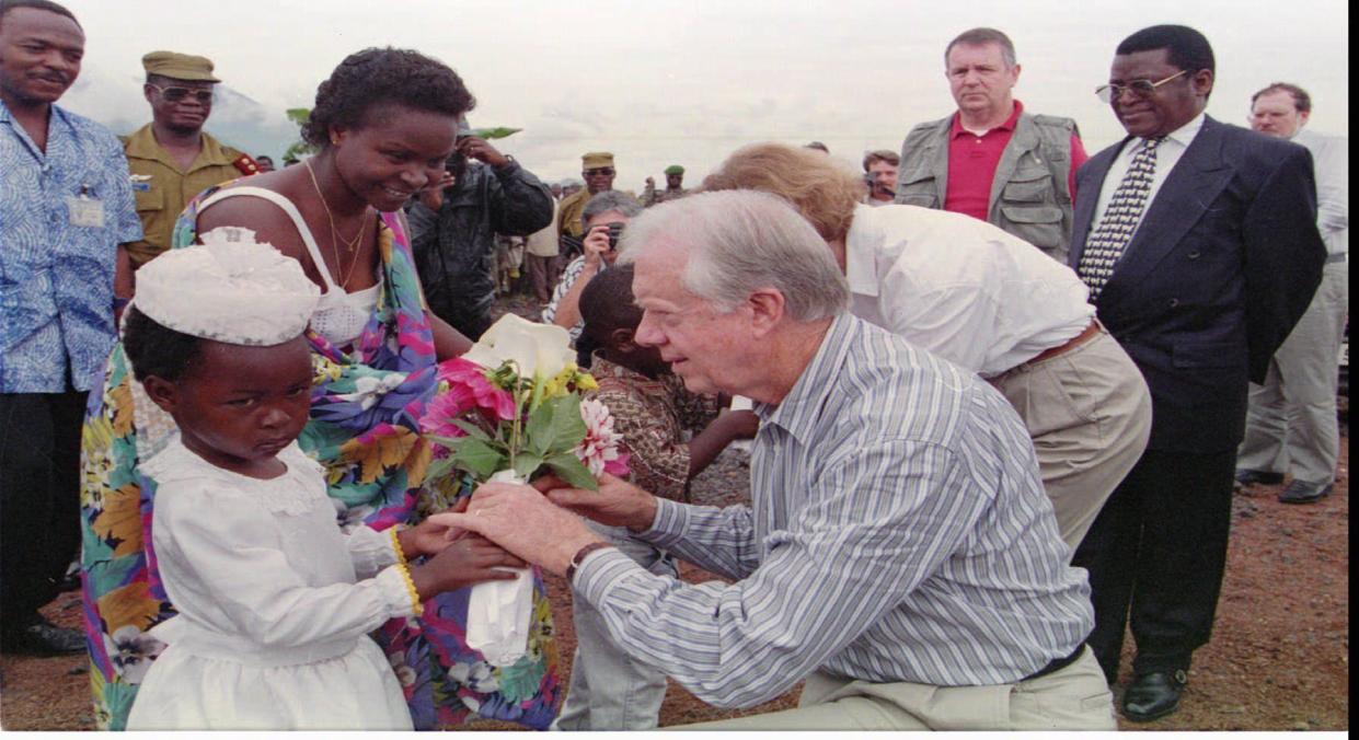 Former President Jimmy Carter receives flowers from a little girl on his arrival at the airport on Nov. 21, 1995, in Goma, Zaire. Former President Carter urged Hutu refugee camp leaders to cooperate with regional officials' plan to repatriate 6,000 refugees a day to Rwanda and Burundi. With his wife, Rosalyn, he is on a fact-finding mission.