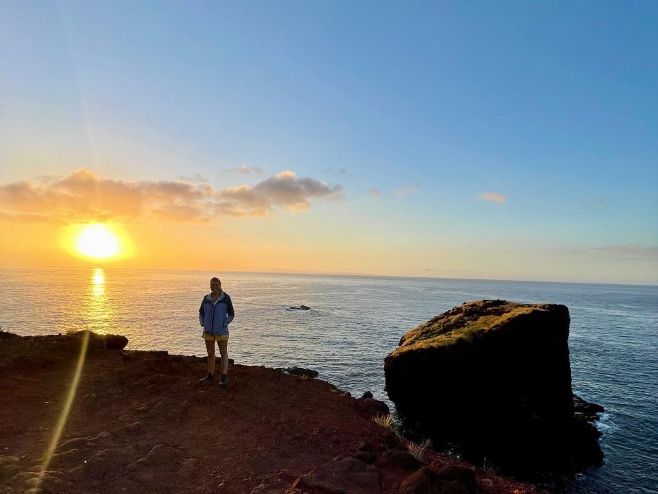 the writer standing next to a rock and sunrise in hawaii
