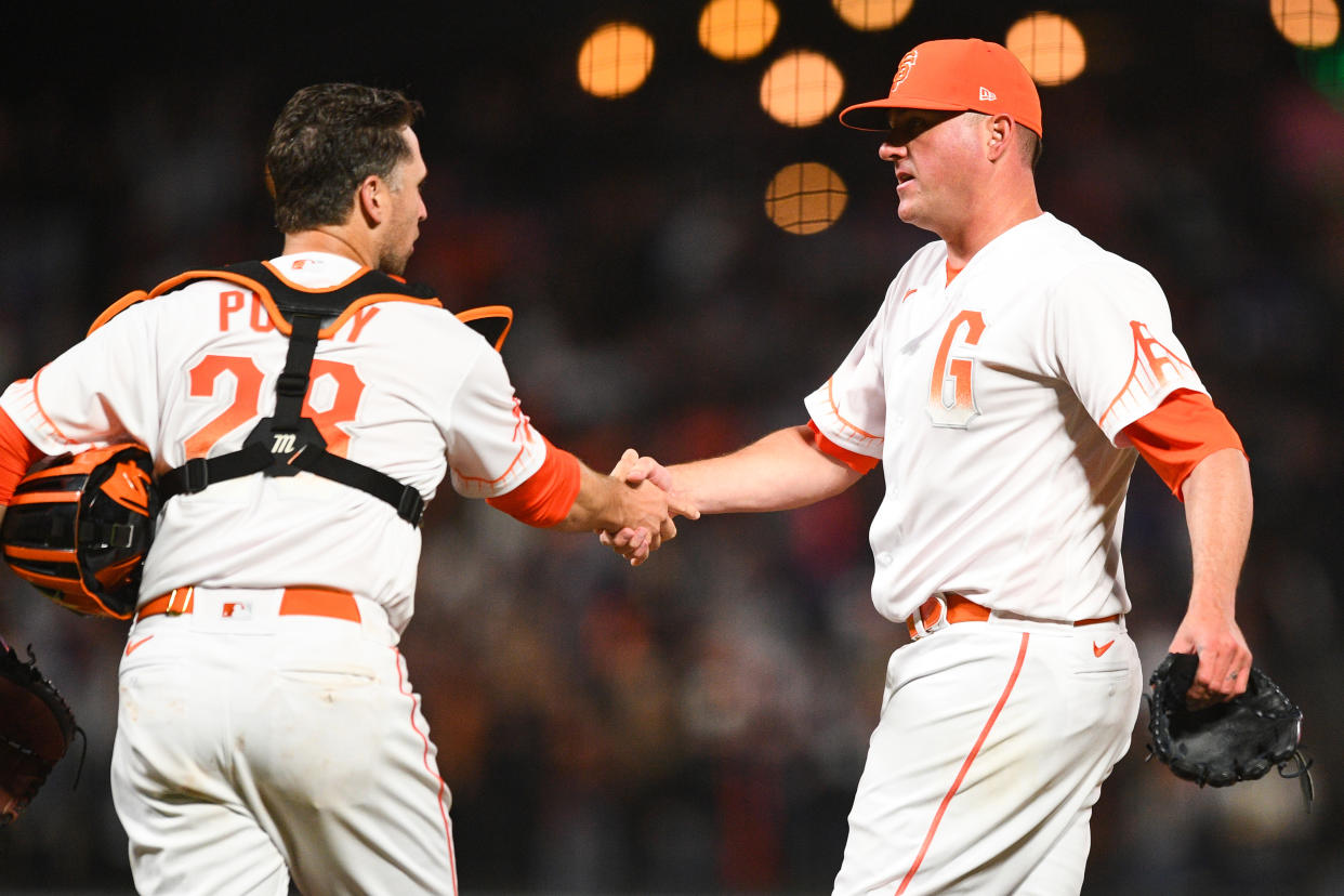 San Francisco Giants pitcher Jake McGee (17) shakes San Francisco Giants catcher Buster Posey's hand after the Giants' win on Tuesday. (Photo by Brian Rothmuller/Icon Sportswire via Getty Images)
