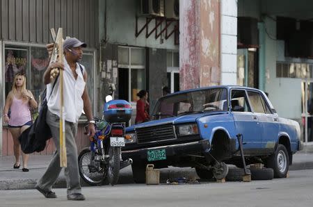 People walk past a Lada that is being repaired on a street in Havana February 7, 2015. REUTERS/Enrique De La Osa