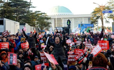 People react after impeachment vote on South Korean President Park Geun-hye was passed, in front of the National Assembly in Seoul, South Korea, December 9, 2016. The sign reads "Impeach Park Geun-hye". News1 via REUTERS