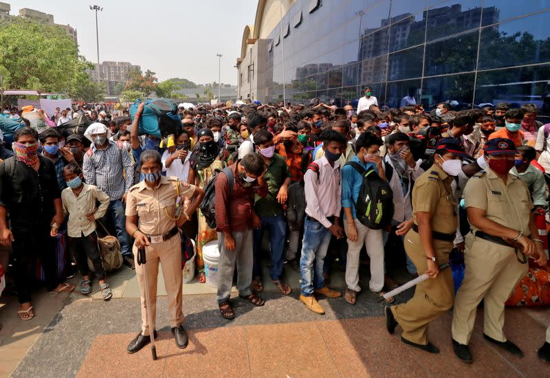 Members of police wearing protective face masks stand guard as people wait to enter the Lokmanya Tilak Terminus railway station, amid the spread of the coronavirus disease (COVID-19) in Mumbai