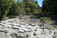 The sun beats down on the dried-up bed of the river Tille in Lux, France, Tuesday Aug. 9, 2022. Burgundy, home to the source of the Seine River which runs through Paris, normally is a very green region. This year, grass turned yellow, depriving livestock from fresh food, and tractors send giant clouds of dust in the air as farmers work in their dry fields. (AP Photo/Nicholas Garriga)