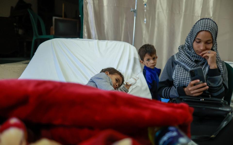 Syrian Fatma Hisham Al Yousef and her children Jommah and Tareq wait for the daily doctors' visit at Bebnine's field hospital - ELISA ODDONE