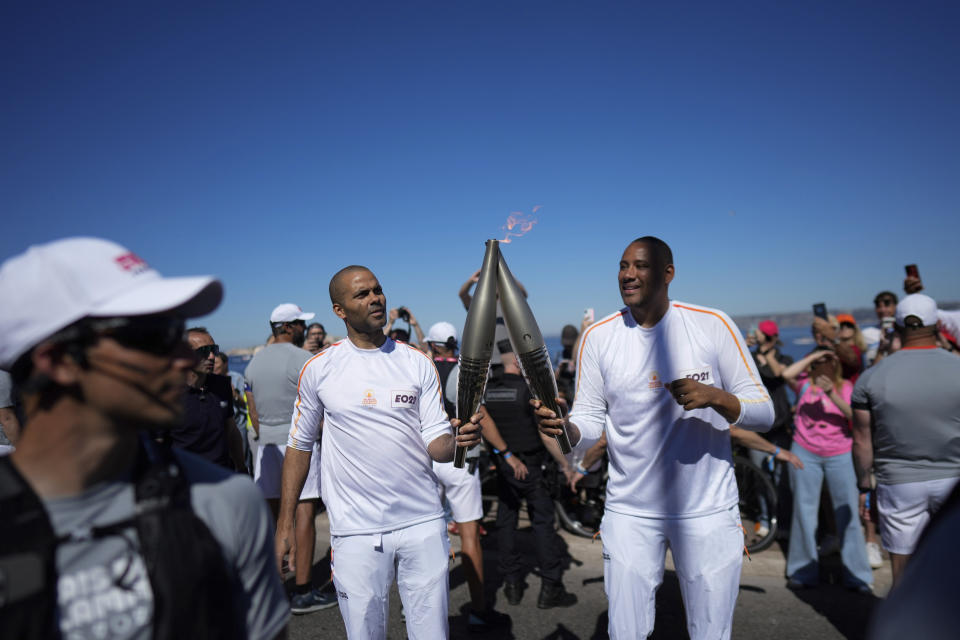 Tony Parker (izquierda) y Gaetan Muller (derecha) en la primera etapa del relevo de la antorcha de los Juegos Olímpicos en Marsella, Francia, el jueves 9 de mayo de 2024. (AP Foto/Thibault Camus)