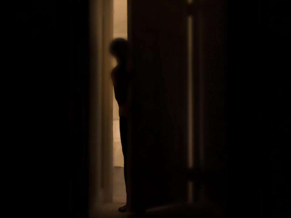 Silhouette of person peeking into dark room