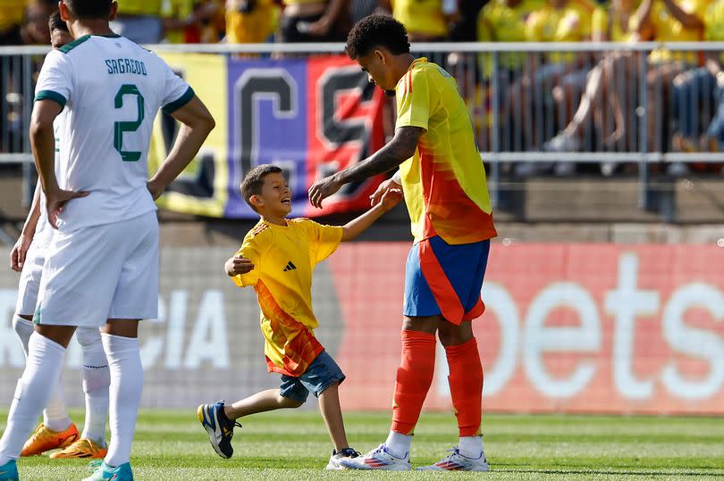 EAST HARTFORD, CT - JUNE 15:  A young fan runs onto the field to get a hug from Luis Díaz #7 of Colombia during the first half of their international friendly match against Bolivia at Pratt & Whitney Stadium on June 15, 2024 in Hartford, Connecticut.