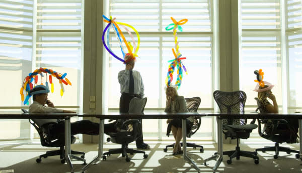 Four business people wearing balloon hats in meeting room