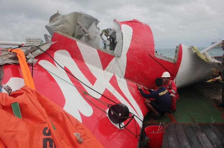 Indonesian officials examine the wreckage from AirAsia flight QZ8501 after it was lifted into the Crest Onyx ship in the Java Sea, on January 10, 2015