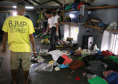 A detainee looks over authorities searching through their belongings for illegal contraband inside the Manila City Jail in metro Manila, Philippines October 16, 2017. REUTERS/Romeo Ranoco