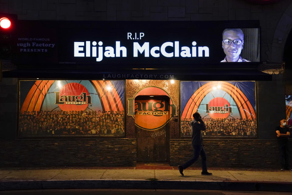 FILE - A man walks past a display showing an image of Elijah McClain outside Laugh Factory during a candlelight vigil for McClain in Los Angeles on Aug. 24, 2020. A group of police officers and paramedics charged in the death of McClain, a 23-year-old Black man who was forcibly restrained and injected with a powerful sedative, are scheduled to appear in court Friday, Jan. 20, 2023, to enter pleas to the allegations. (AP Photo/Jae C. Hong, File)