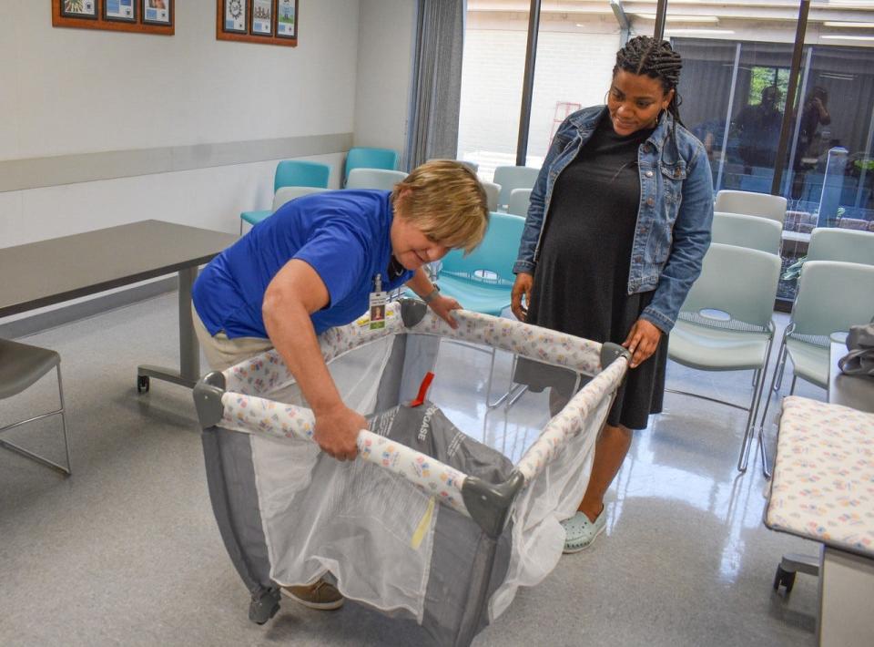 Sandusky County Public Health Nurse, Jane Molyet, left, demonstrates a Pack ‘n Play portable crib for expectant mother, Chervon Crickie. Crickie will receive a free Pack ‘n Play through the Cribs for Kids program.
