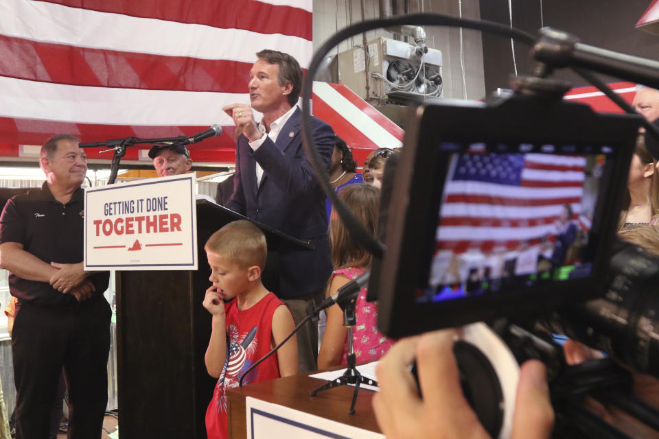 Virginia Gov. Glenn Youngkin, at podium, gestures as he speaks before signing the budget bill at a ceremony at a grocery store Tuesday June 21, 2022, in Richmond, Va. The Virginia General Assembly passed the budget earlier in the week. (AP Photo/Steve Helber)