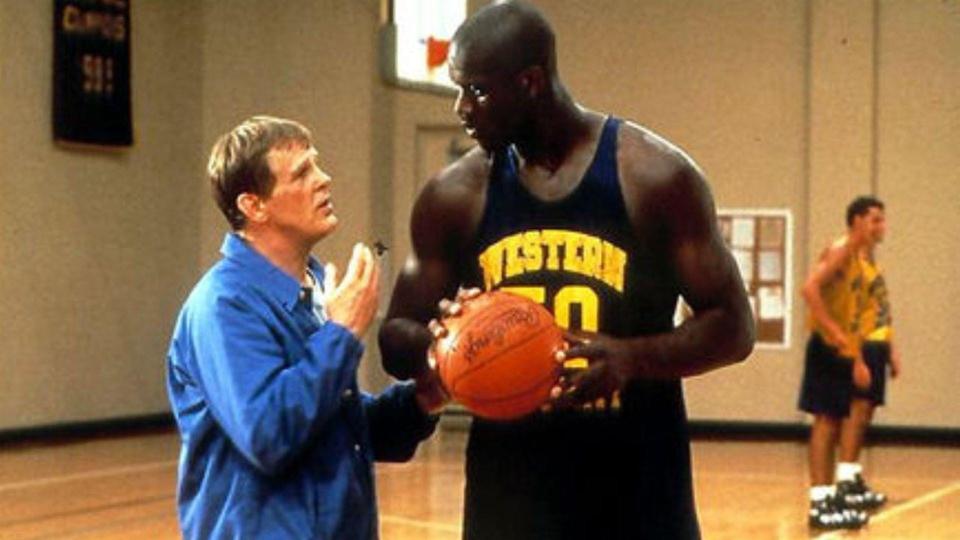 Nick Nolte in a blue jacket talking to Shaquille O'Neal holding a basketball