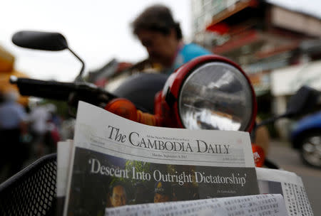 A woman buys the final issue of The Cambodia Daily newspaper at a store along a street in Phnom Penh, Cambodia, September 4, 2017. REUTERS/Samrang Pring